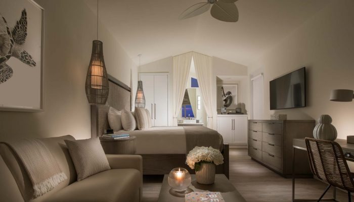 interior of bungalow, with beige accents, a king bed, couch and desk