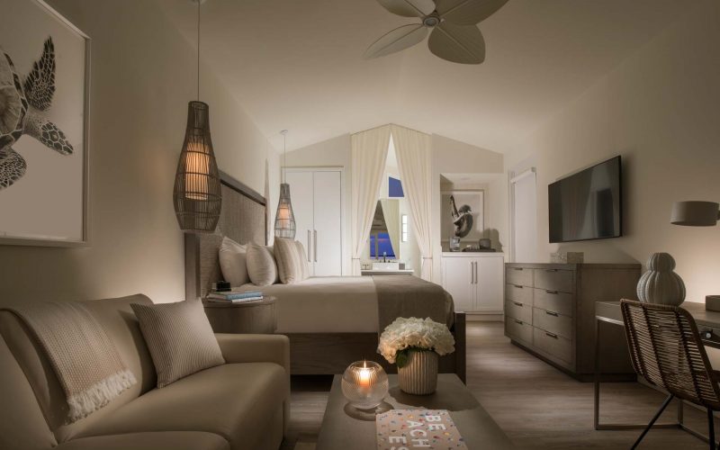 interior of bungalow, with beige accents, a king bed, couch and desk