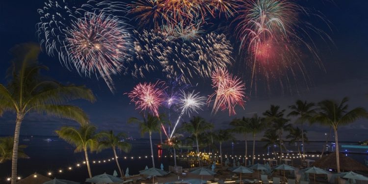 an outdoor swimming pool at night with fireworks over the water