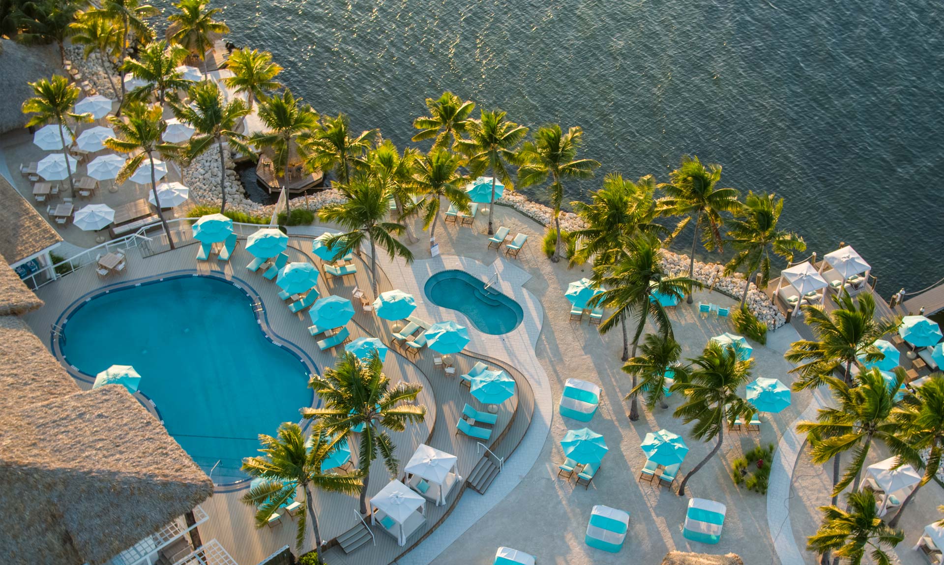 The beach with palm trees and umbrellas on the ocean at Bungalows Key Largo