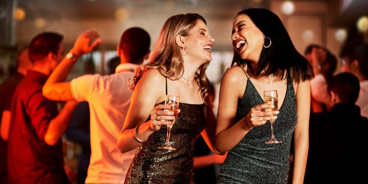 Cropped shot of two cheerful young women having drinks while dancing on the dance floor of a club at night