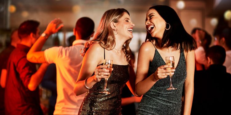 Having a great night? Cropped shot of two cheerful young women having drinks while dancing on the dance floor of a club at night