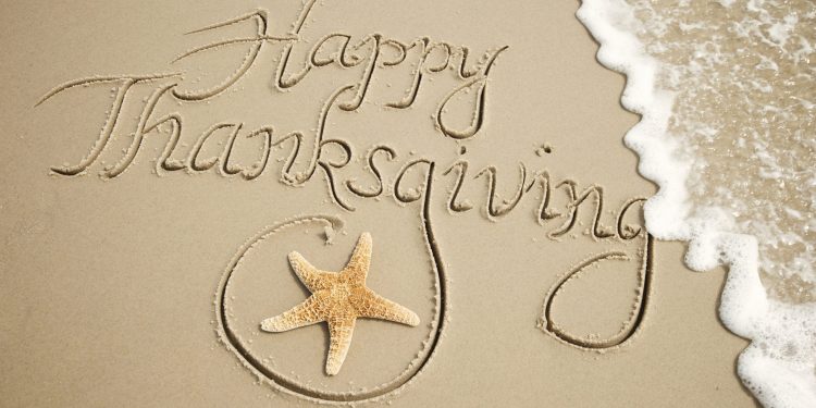 Happy Thanksgiving Message Handwritten Outdoors with White Wave Happy Thanksgiving message handwritten outdoors in smooth brown sand with starfish and frothy white wave