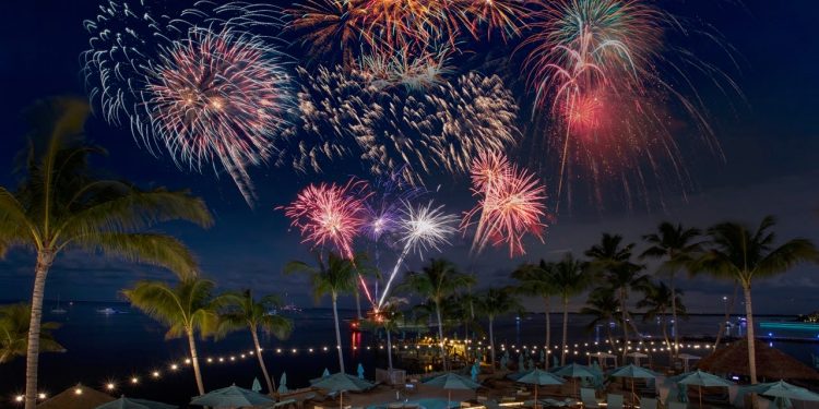 an outdoor swimming pool at night with fireworks over the water